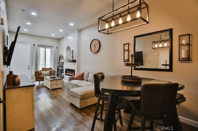 dining area with a large fireplace and dark hardwood / wood-style flooring