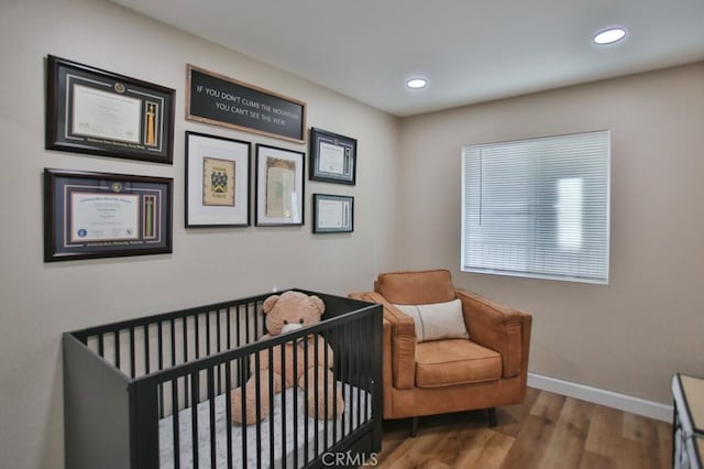 bedroom featuring hardwood / wood-style flooring and a crib