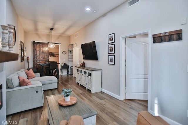 living room with a barn door and wood-type flooring