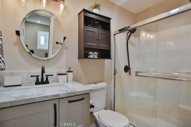 bathroom featuring toilet, a shower with door, and vanity