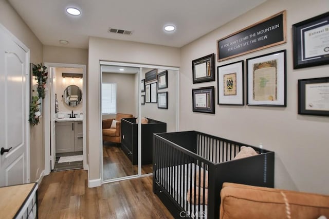 interior space with a nursery area, dark hardwood / wood-style flooring, sink, a closet, and ensuite bathroom