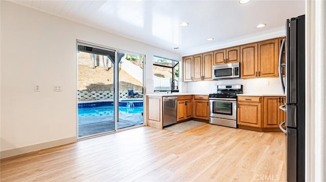 kitchen with stainless steel appliances, light hardwood / wood-style floors, and sink