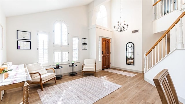 entrance foyer featuring a towering ceiling, a chandelier, and wood-type flooring