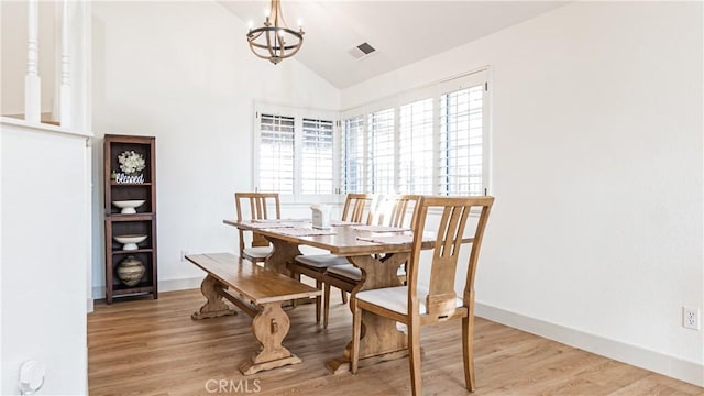 dining space with vaulted ceiling, light hardwood / wood-style flooring, and an inviting chandelier