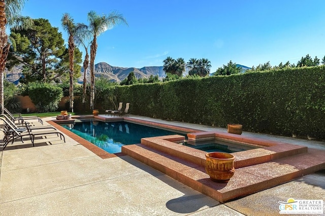 view of pool with a patio area, a mountain view, and an in ground hot tub