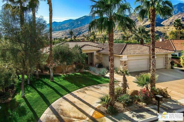 mediterranean / spanish home featuring a front lawn, a garage, and a mountain view