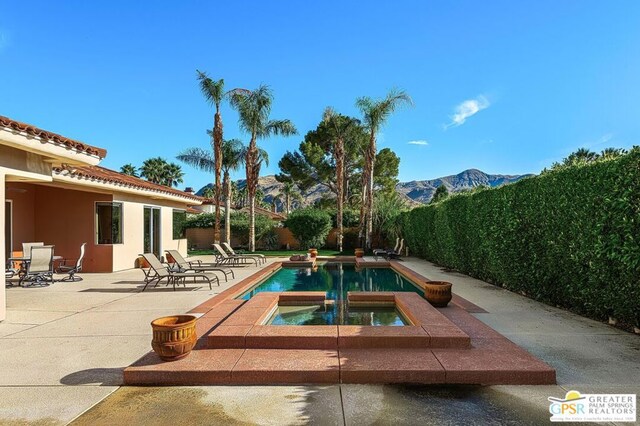 view of swimming pool featuring a mountain view, a patio, and an in ground hot tub