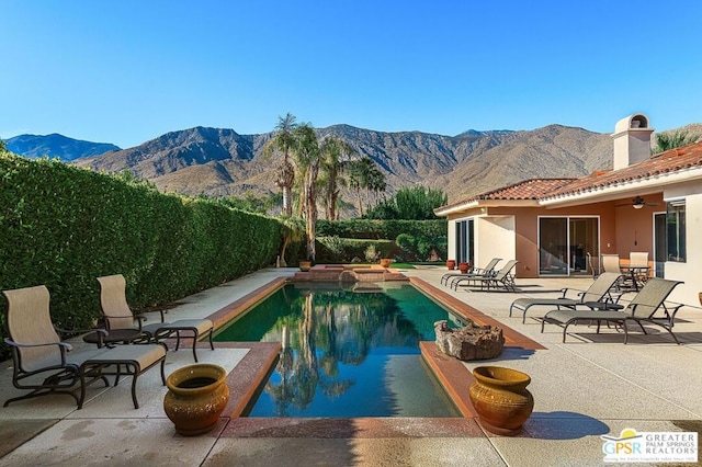 view of swimming pool with ceiling fan, a mountain view, and a patio