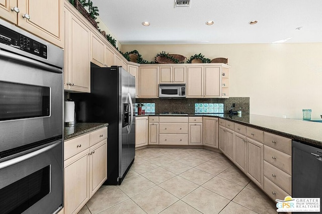 kitchen featuring decorative backsplash, light tile patterned floors, stainless steel appliances, and dark stone counters