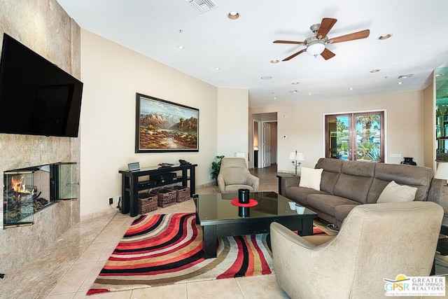 living room featuring ceiling fan, light tile patterned floors, and a fireplace