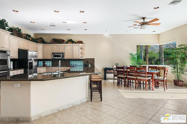 kitchen featuring stainless steel appliances, dark stone counters, decorative backsplash, sink, and light tile patterned floors