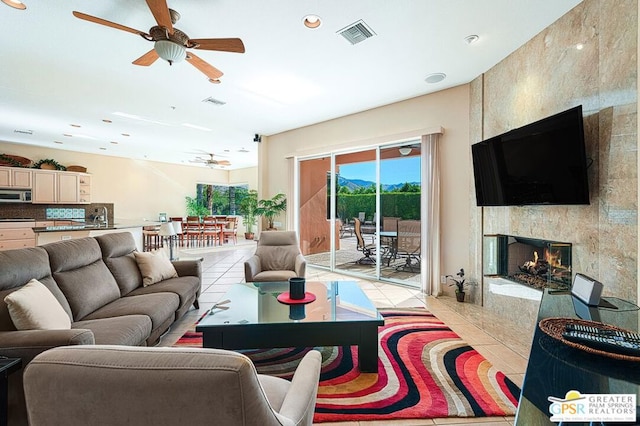 living room with ceiling fan, sink, light tile patterned floors, and a premium fireplace