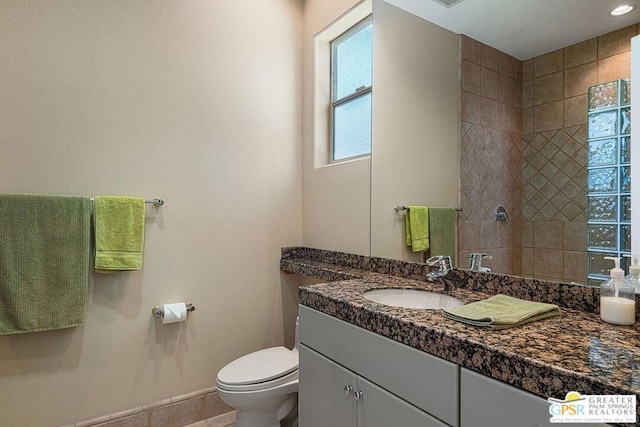 bathroom with toilet, vanity, and tiled shower