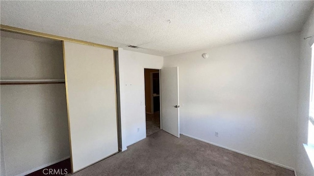 unfurnished bedroom with a textured ceiling, a closet, and carpet