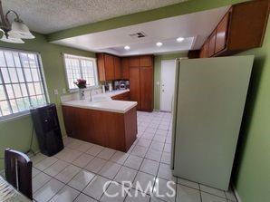 kitchen featuring a textured ceiling, light tile patterned floors, kitchen peninsula, and white fridge