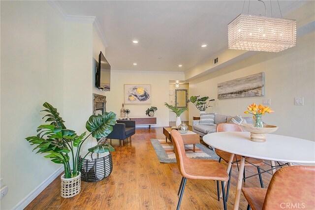 dining space featuring hardwood / wood-style flooring, ornamental molding, and an inviting chandelier