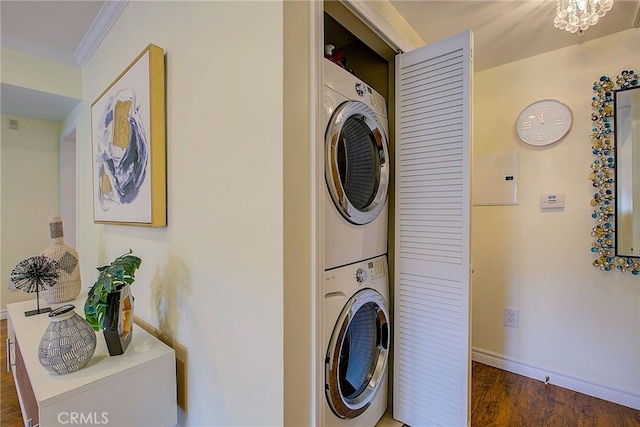 clothes washing area with stacked washer and dryer, dark wood-type flooring, ornamental molding, and a notable chandelier