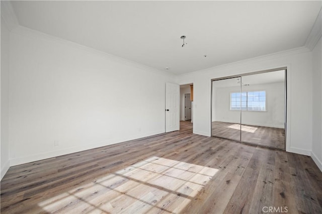 unfurnished bedroom with a closet, crown molding, and light hardwood / wood-style flooring