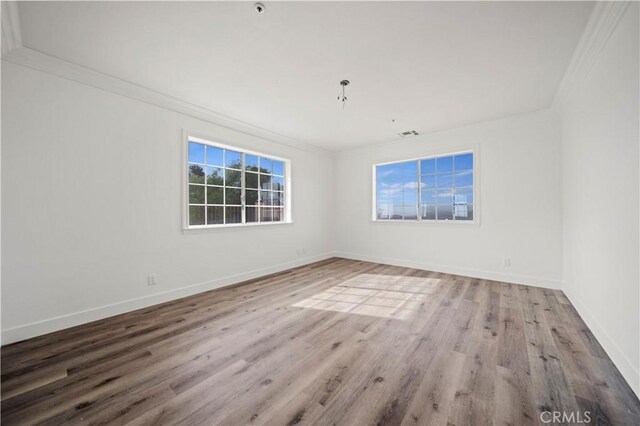 empty room featuring ornamental molding and light hardwood / wood-style flooring