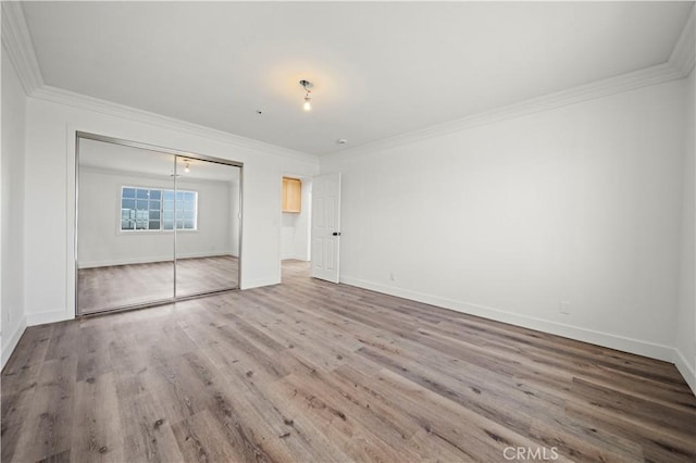 unfurnished bedroom featuring a closet, crown molding, and wood-type flooring