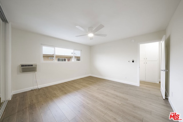 spare room with light hardwood / wood-style floors, a wall unit AC, and ceiling fan