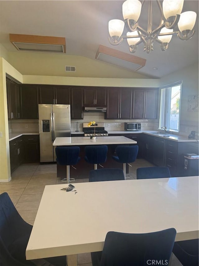 kitchen featuring pendant lighting, stainless steel appliances, a notable chandelier, and a kitchen island