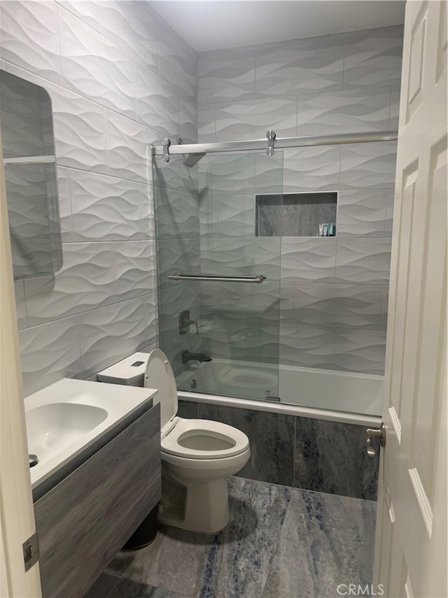 full bathroom featuring toilet, tiled shower / bath combo, tile walls, and vanity