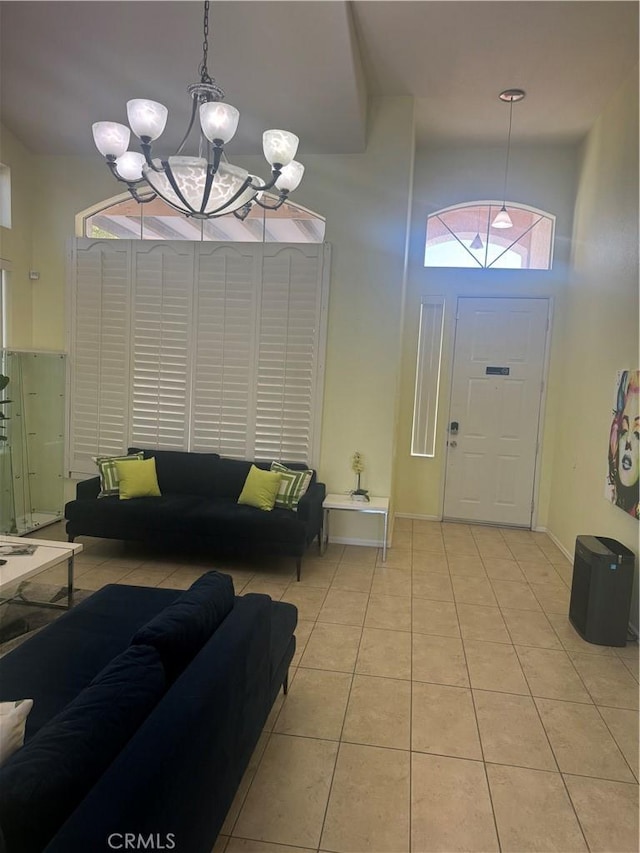 entryway featuring light tile patterned flooring, a high ceiling, and a chandelier