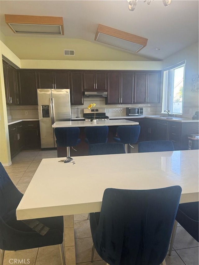 kitchen featuring appliances with stainless steel finishes, a breakfast bar area, and an island with sink