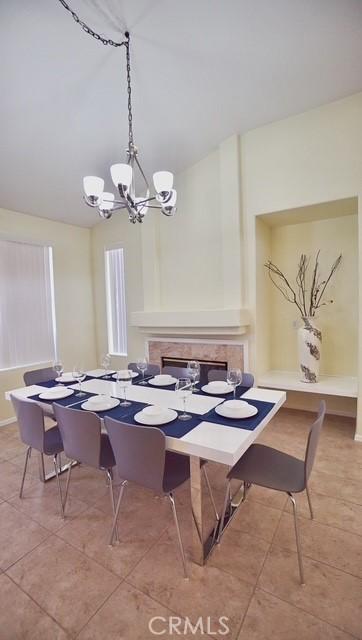 tiled dining room featuring vaulted ceiling and a notable chandelier