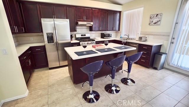 kitchen featuring a kitchen bar, appliances with stainless steel finishes, light tile patterned flooring, and a kitchen island