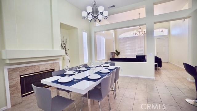 tiled dining area featuring a notable chandelier, a high end fireplace, and a towering ceiling