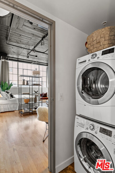 laundry room featuring wood-type flooring and stacked washer / drying machine