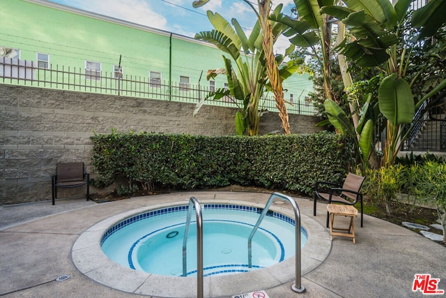 view of swimming pool featuring a hot tub and a patio