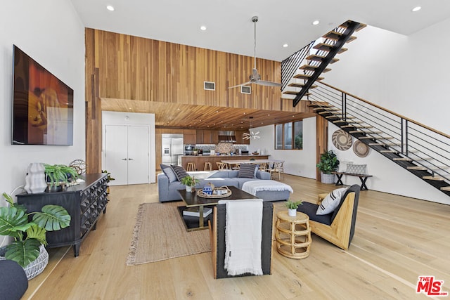 living room with ceiling fan, light hardwood / wood-style floors, and a high ceiling