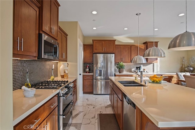 kitchen with backsplash, pendant lighting, sink, appliances with stainless steel finishes, and an island with sink