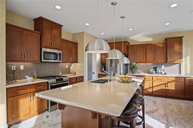 kitchen featuring stainless steel appliances, decorative backsplash, a kitchen bar, and a kitchen island with sink