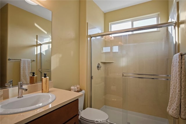 bathroom with toilet, a shower with shower door, and vanity