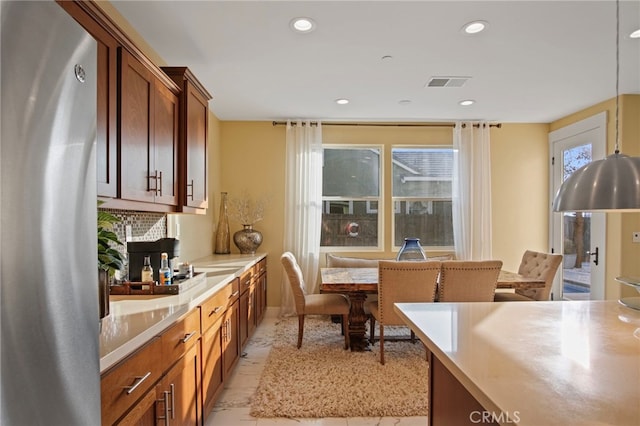 kitchen with decorative light fixtures, light tile patterned flooring, stainless steel fridge, and tasteful backsplash