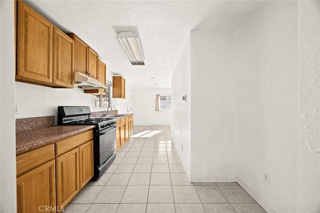 kitchen with sink, black gas stove, light tile patterned floors, and a textured ceiling