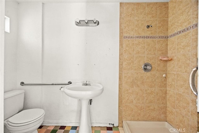 bathroom featuring tiled shower and toilet