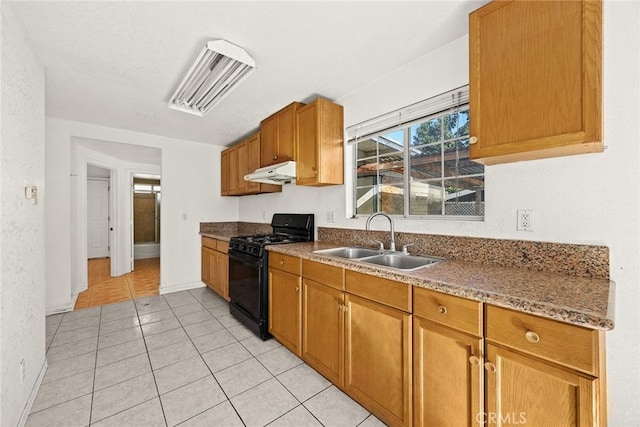 kitchen with sink, stone countertops, gas stove, and light tile patterned flooring