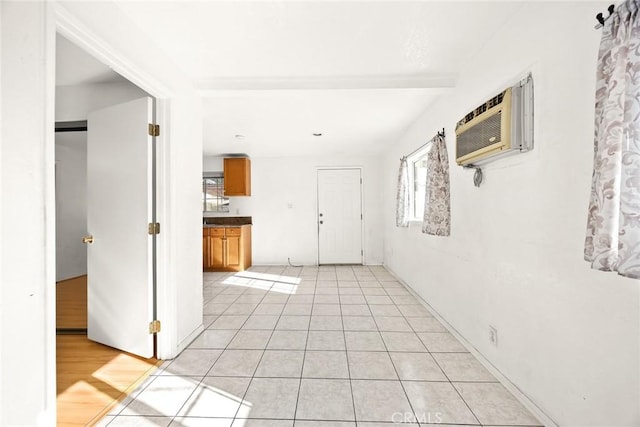 interior space with light tile patterned floors, an AC wall unit, and beamed ceiling