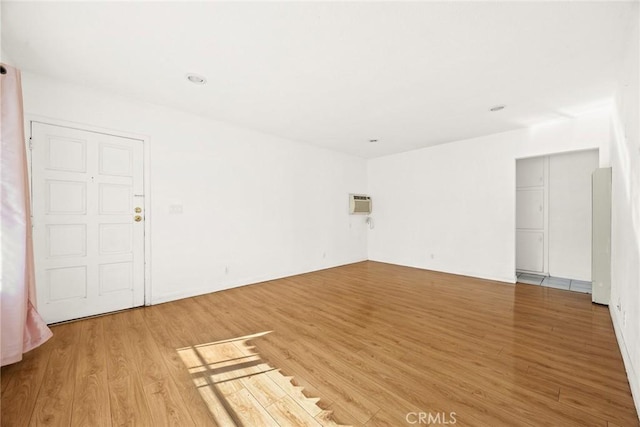 empty room with light wood-type flooring and a wall mounted air conditioner