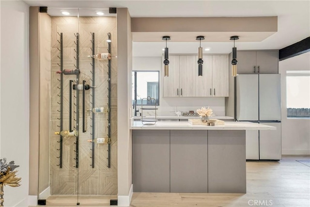 kitchen featuring gray cabinets, pendant lighting, kitchen peninsula, light hardwood / wood-style flooring, and white refrigerator