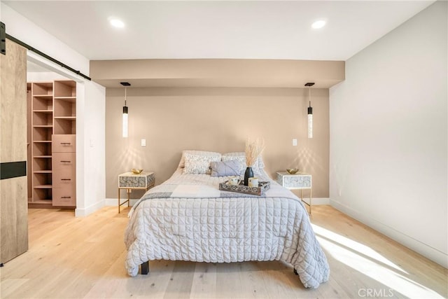 bedroom featuring a walk in closet, a barn door, and hardwood / wood-style flooring