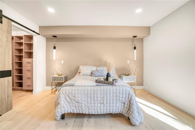 bedroom with baseboards, a barn door, wood finished floors, and recessed lighting
