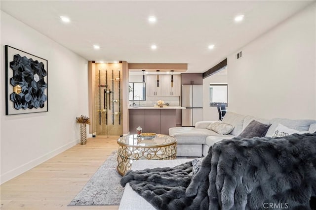 living room with baseboards, recessed lighting, light wood-style flooring, and visible vents