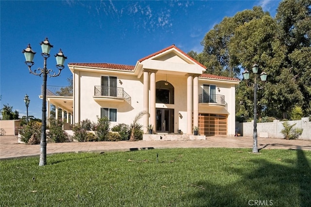 view of front of property featuring a garage, a balcony, and a front yard