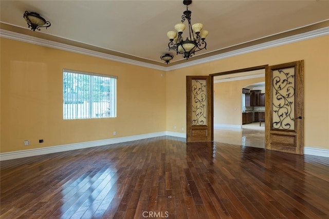 spare room with an inviting chandelier, ornamental molding, and hardwood / wood-style flooring